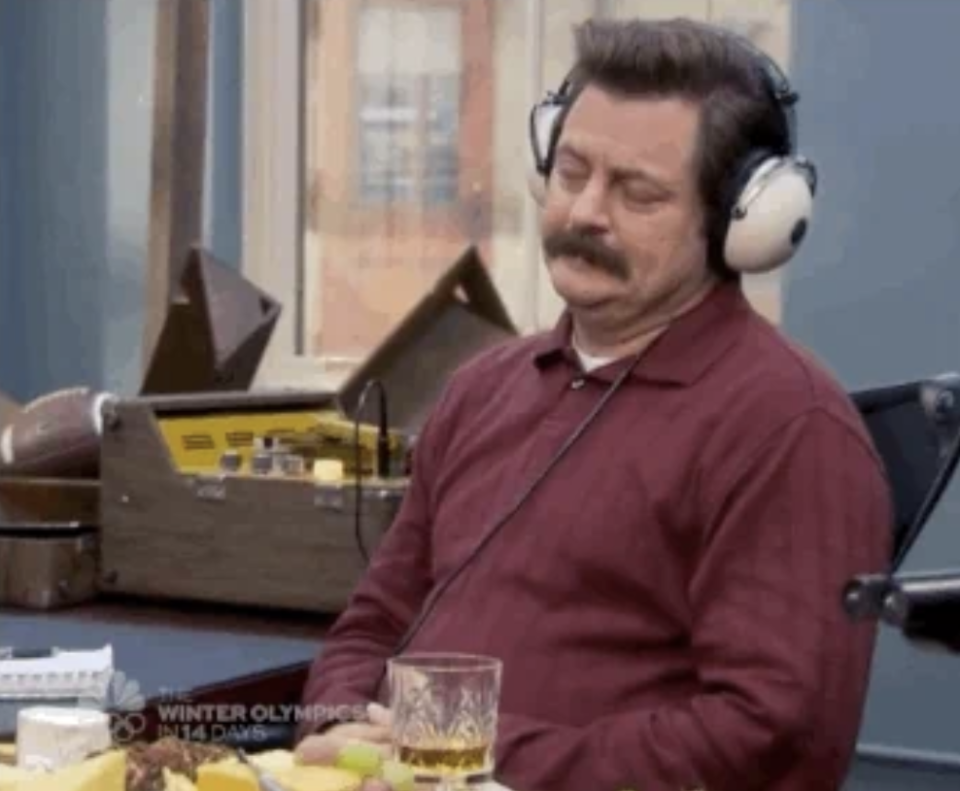 A person with headphones relaxes in a chair with eyes closed near a table of food and drinks