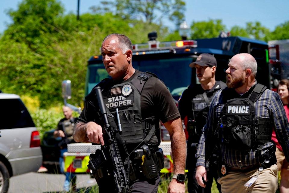 Several law enforcement officers walk on a street.